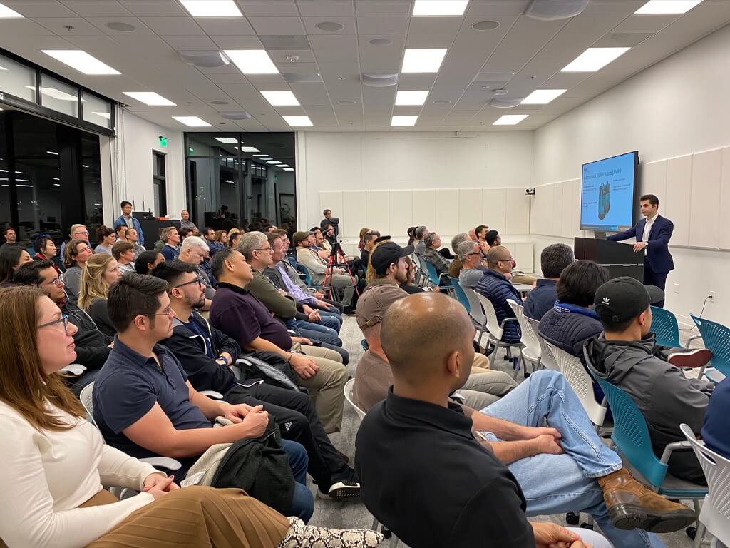 An audience watches as someone presents at a podium