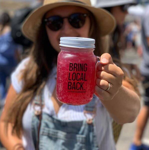 a mason jar filled with bright pink kombucha reads "bring local back"