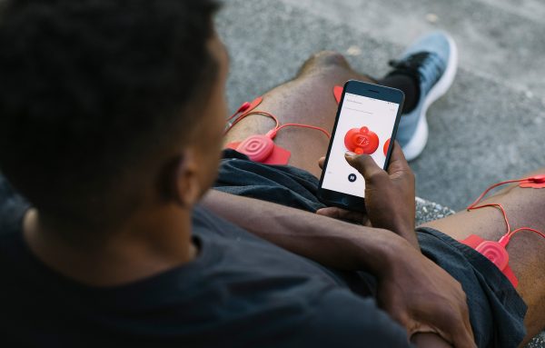 An over-the-shoulder look at a PowerDot user using the PowerDot app as he sits outside