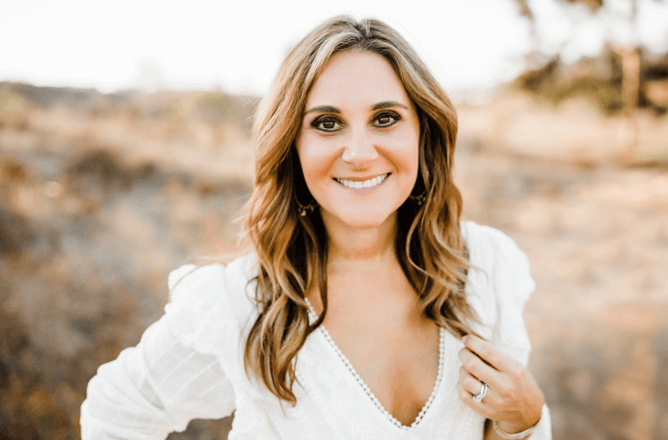 Rebecca Traverso stands in a field, wearing a white dress.