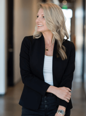 Shannon Williams, wearing a black blazer, looks to the left and smiles.