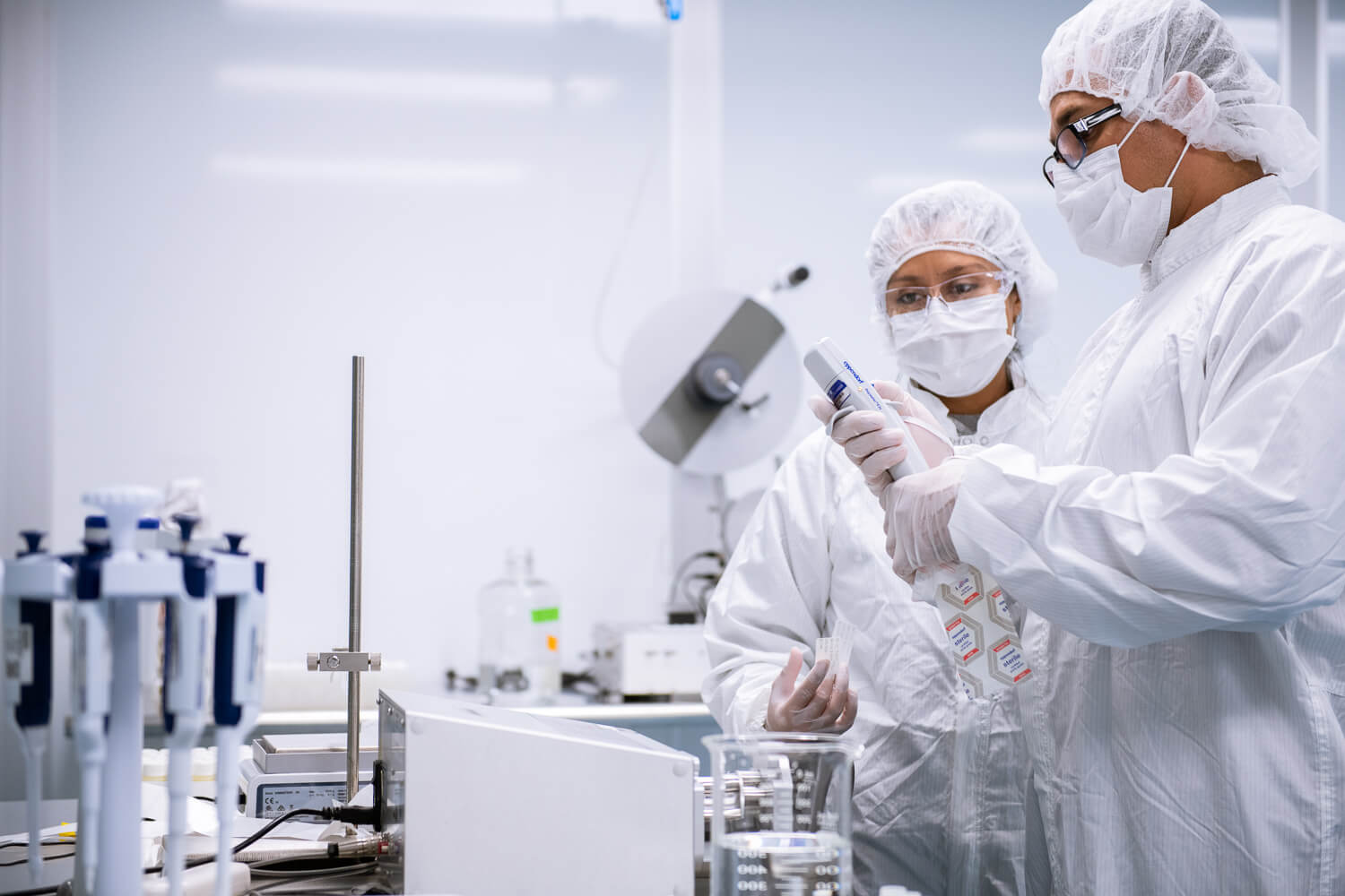 Two employees dressed in white PPE work in a lab