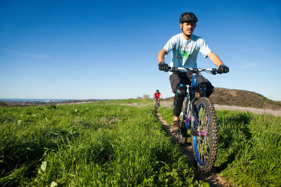 A young man mountainbikes throug a patch of grass