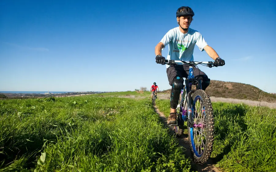 A young man mountainbikes throug a patch of grass