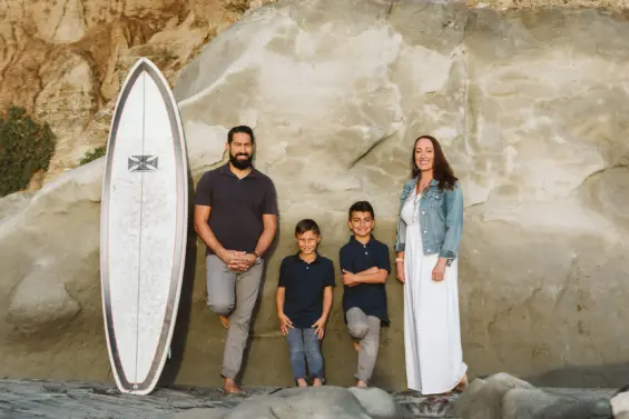 Taryne Haskamp and family posing next to surfboard for photoshoot